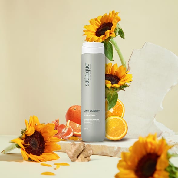 A blank label tube has a golden lid featured on plaster pedestal against white background, sunflowers with brilliant yellow as an accent of photo. Mockup for advertising, copy space